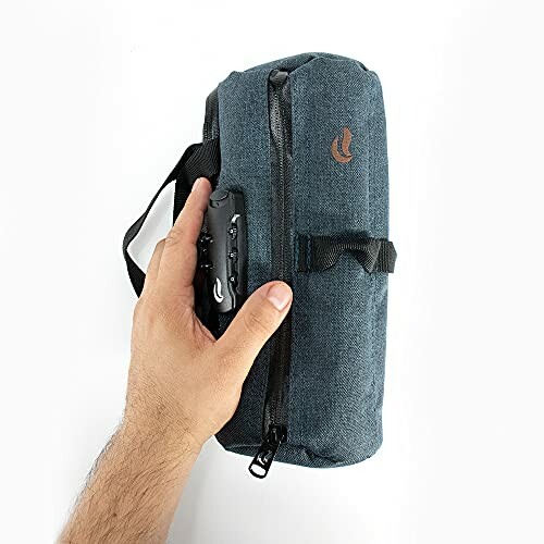 Hand holding a small blue travel bag with zipper and handle