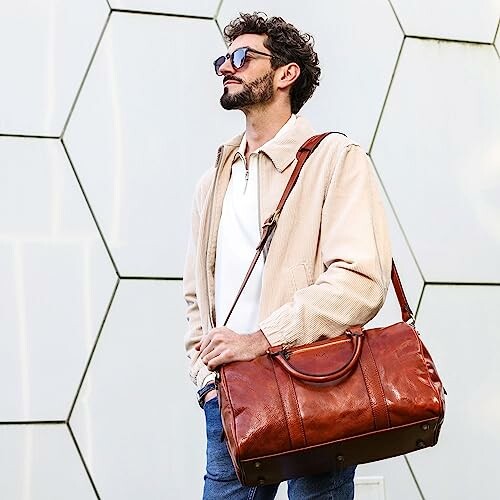 Man wearing sunglasses carrying a brown leather bag.