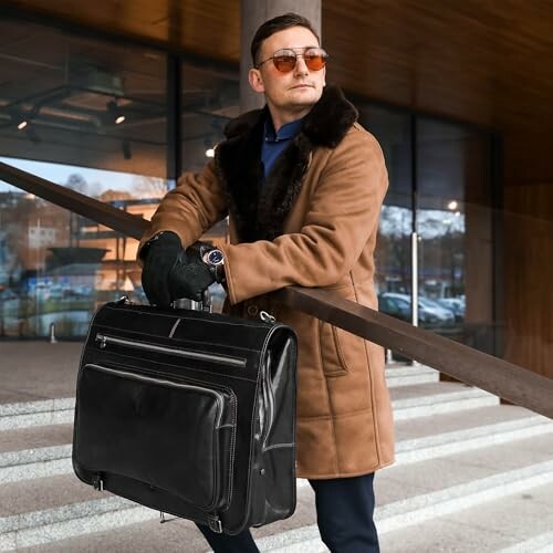 Man in coat holding a leather bag on stairs